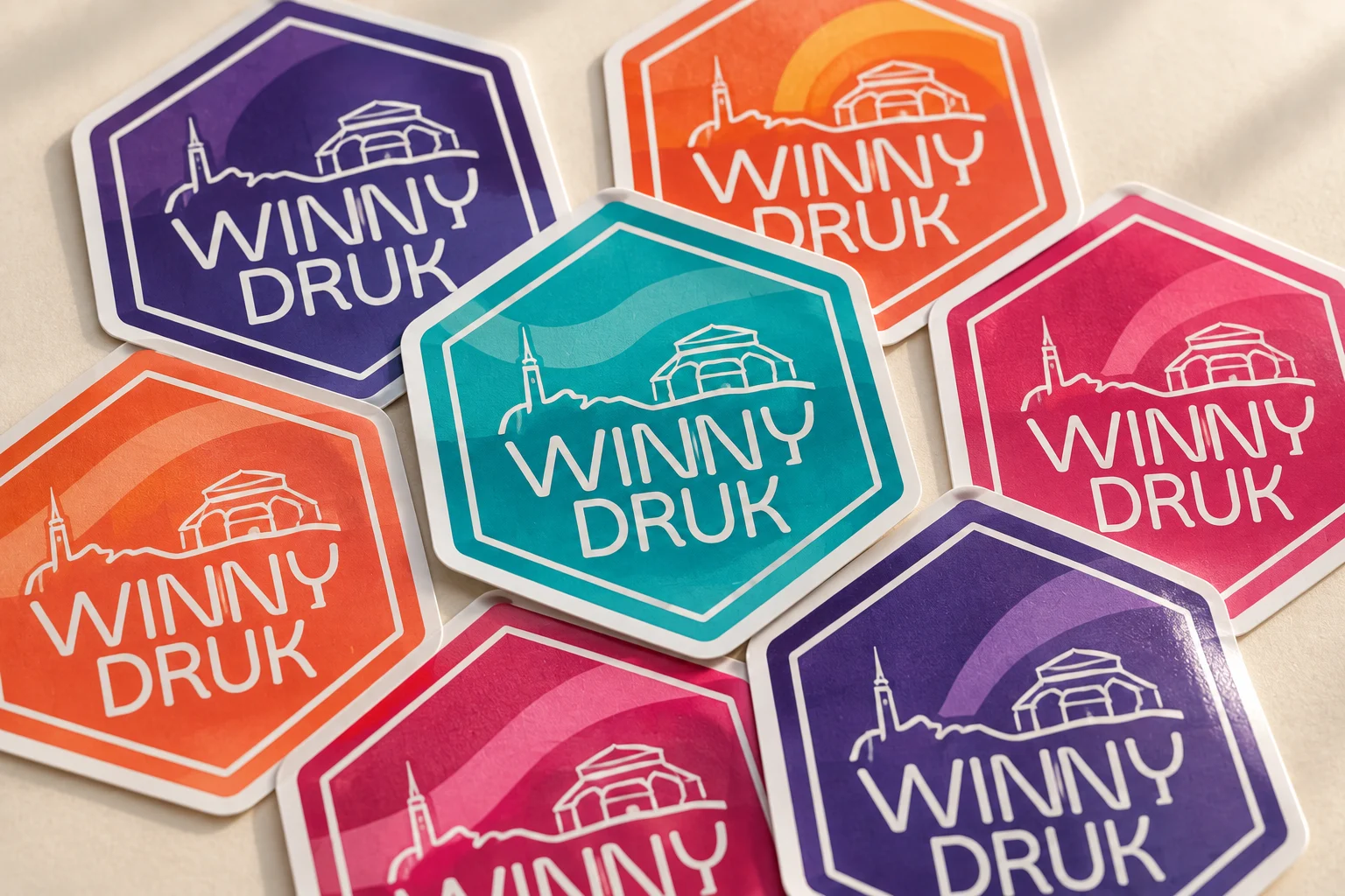 Wizualizacja kolorowych naklejek z logo Winny Druk na stole