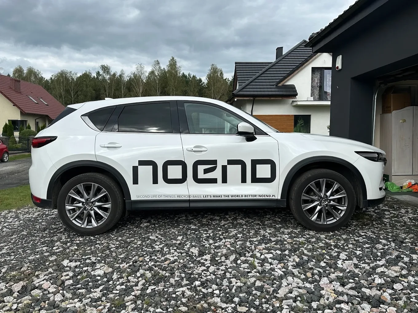Biały samochód z reklamowym napisem NOEND na drzwiach