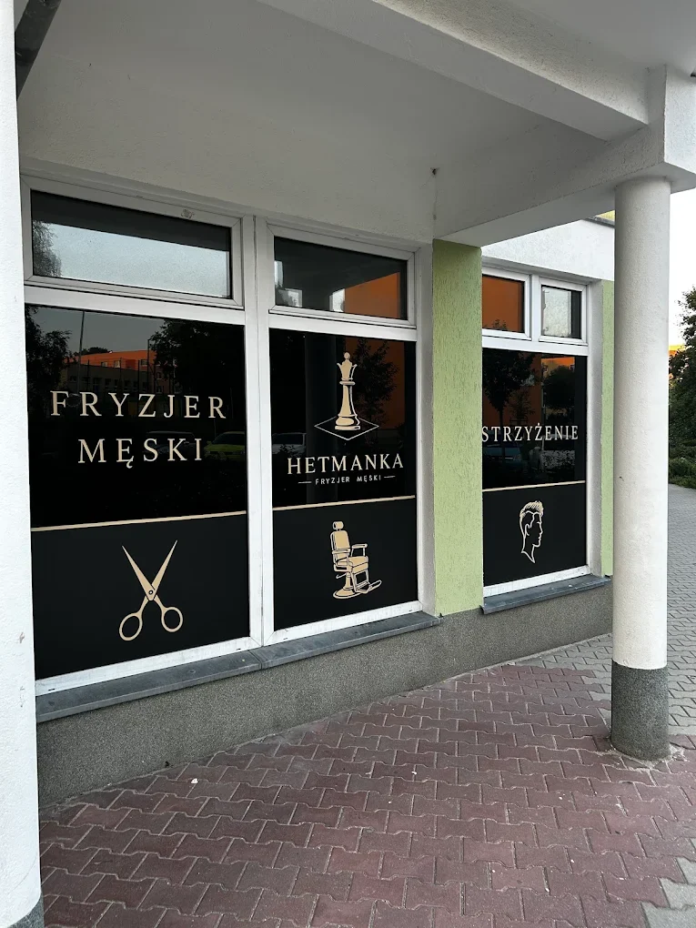 Oklejona witryna fryzjera z napisami i grafiką nożyczek